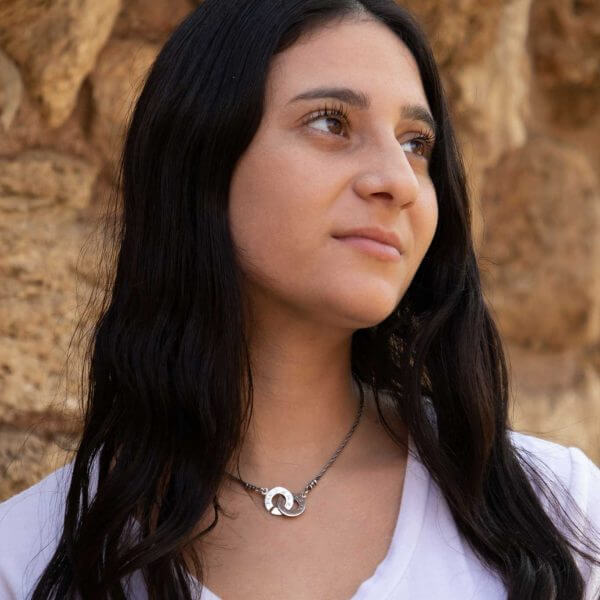 A woman wearing a silver pendant consisting of two discs combined with each other and engraved with ancient Hebrew writing